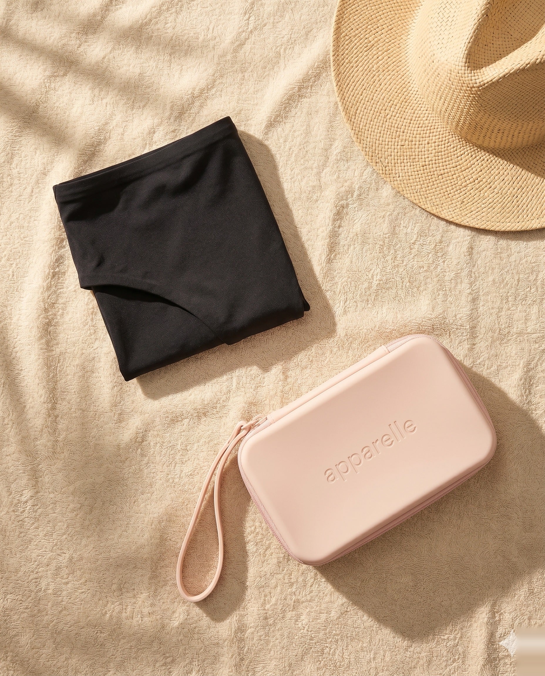 Bikini menstrual Apparelle doblado sobre toalla junto al Neceser Waterproof rosa — kit listo para llevar una segunda unidad y mantenerla aislada del bañador mojado.