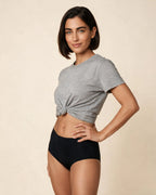 Modelo con braga menstrual de tiro alto Apparelle en negro y camiseta gris anudada, de rodilla hacia arriba