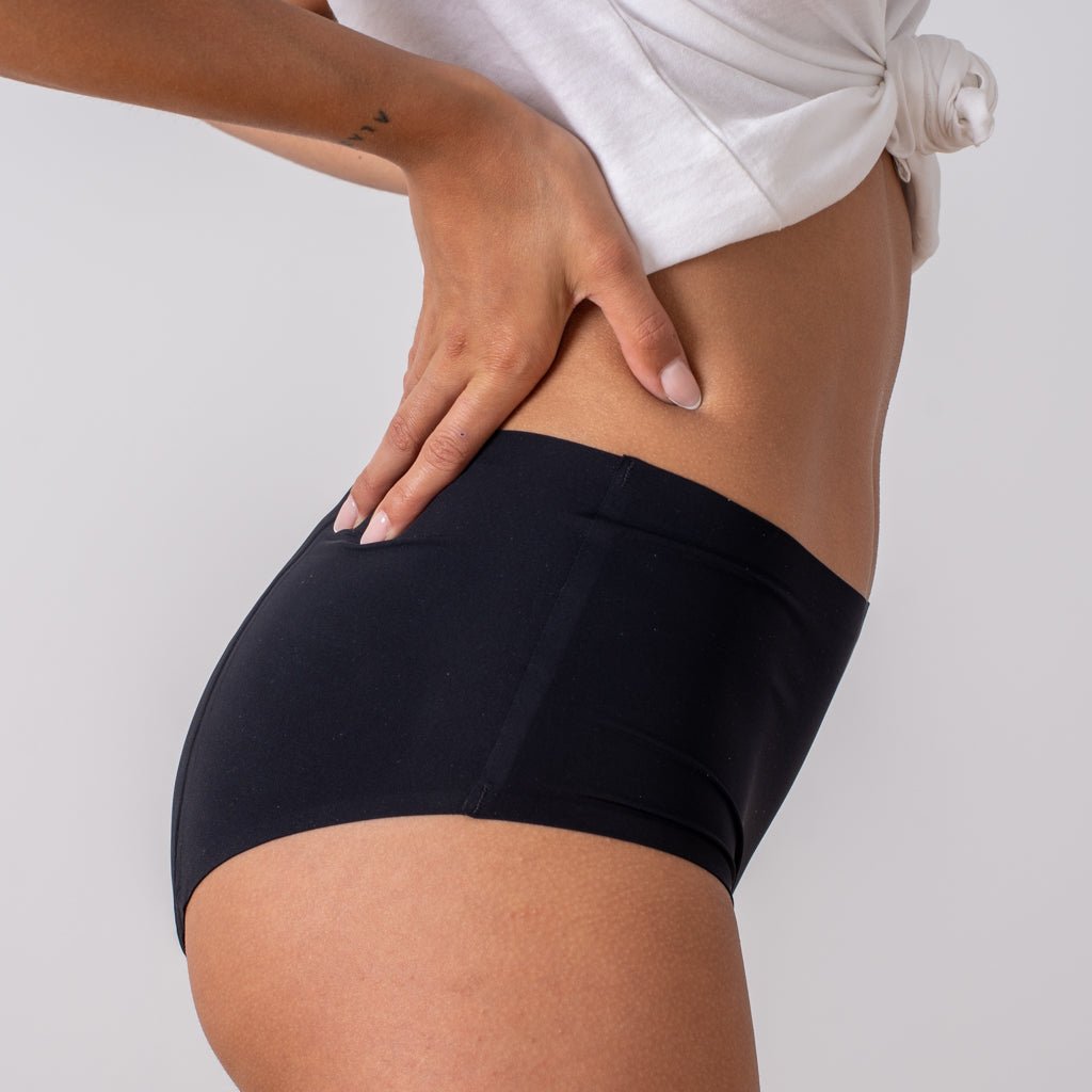 Braga menstrual tiro alto Apparelle negra - vista lateral trasera mostrando ajuste en cadera y cintura alta