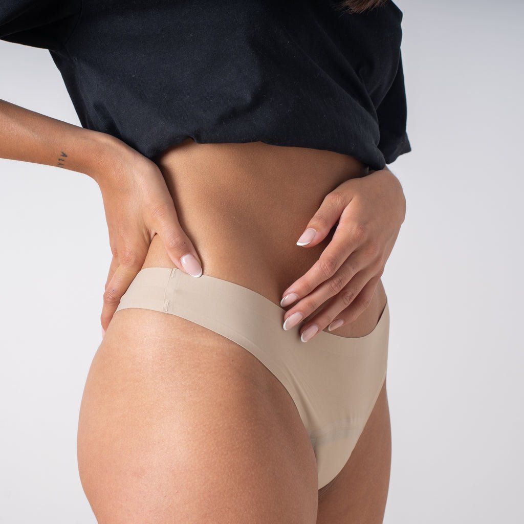 Tanga menstrual Apparelle color nude - vista lateral en modelo mostrando corte invisible y tono piel